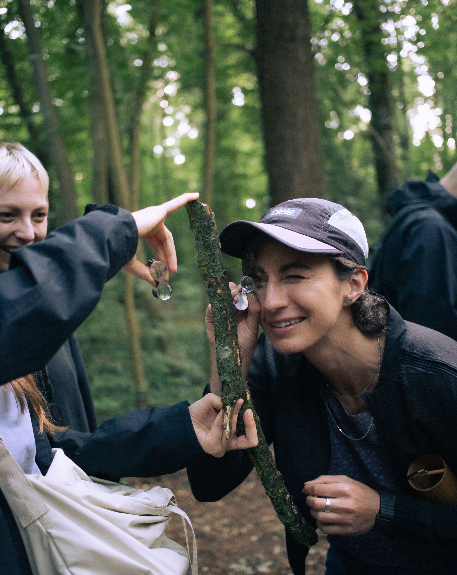 A woman uses a magnifying lens to examine some beautiful lichen on a piece of wood.